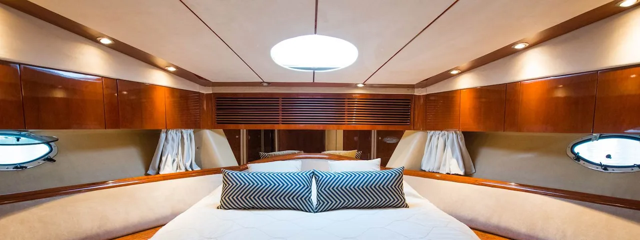 Luxury yacht interior: Spacious cabin with comfortable bed, wooden finishes, and ambient lighting for ultimate relaxation at sea