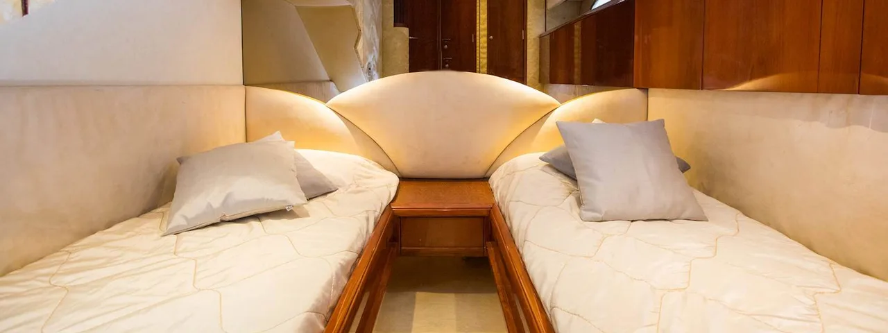 Luxurious yacht cabin with twin beds, plush pillows, and warm lighting. Elegant wood finishes and cozy atmosphere for Elafiti Islands cruise.