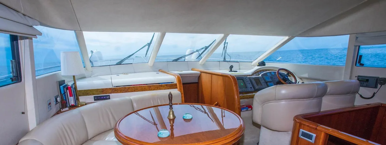 Luxury yacht interior: Elegant seating area with curved leather sofa, wooden table, and steering console on Elafiti Islands tour
