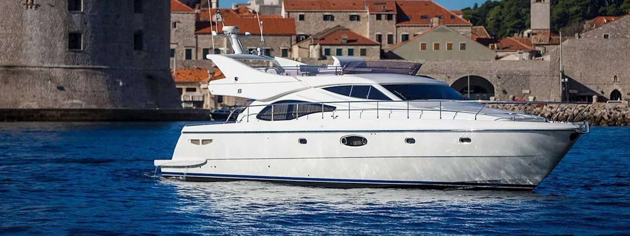 Luxury yacht sailing past Dubrovnik old town walls, Croatia. 