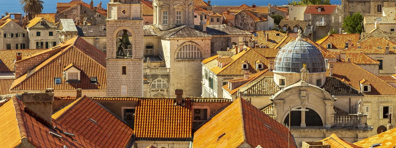 Panoramic aerial view of Dubrovnik Old Town terracotta rooftops, cathedral dome and blue Adriatic Sea, Croatia