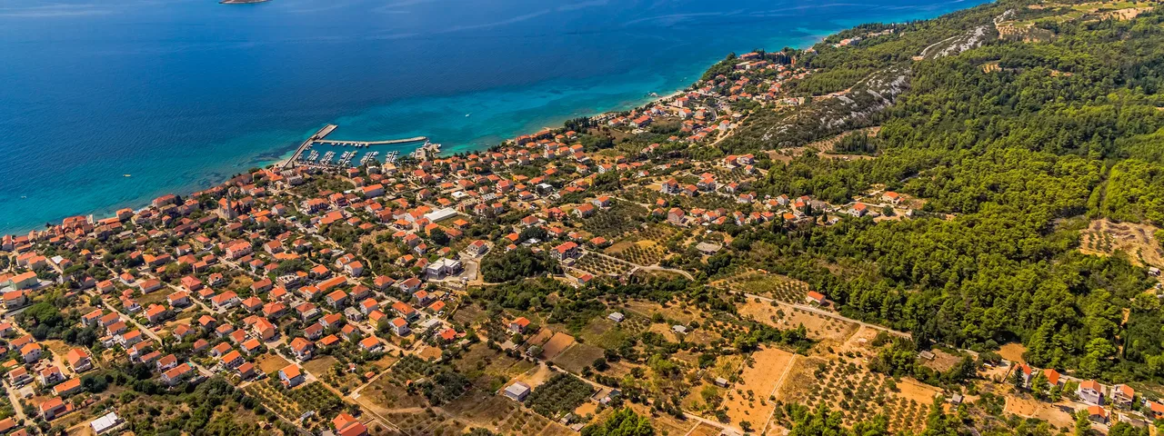 Aerial panorama of Korčula island and Pelješac channel with coastal village, olive groves and turquoise Adriatic Sea, Croatia