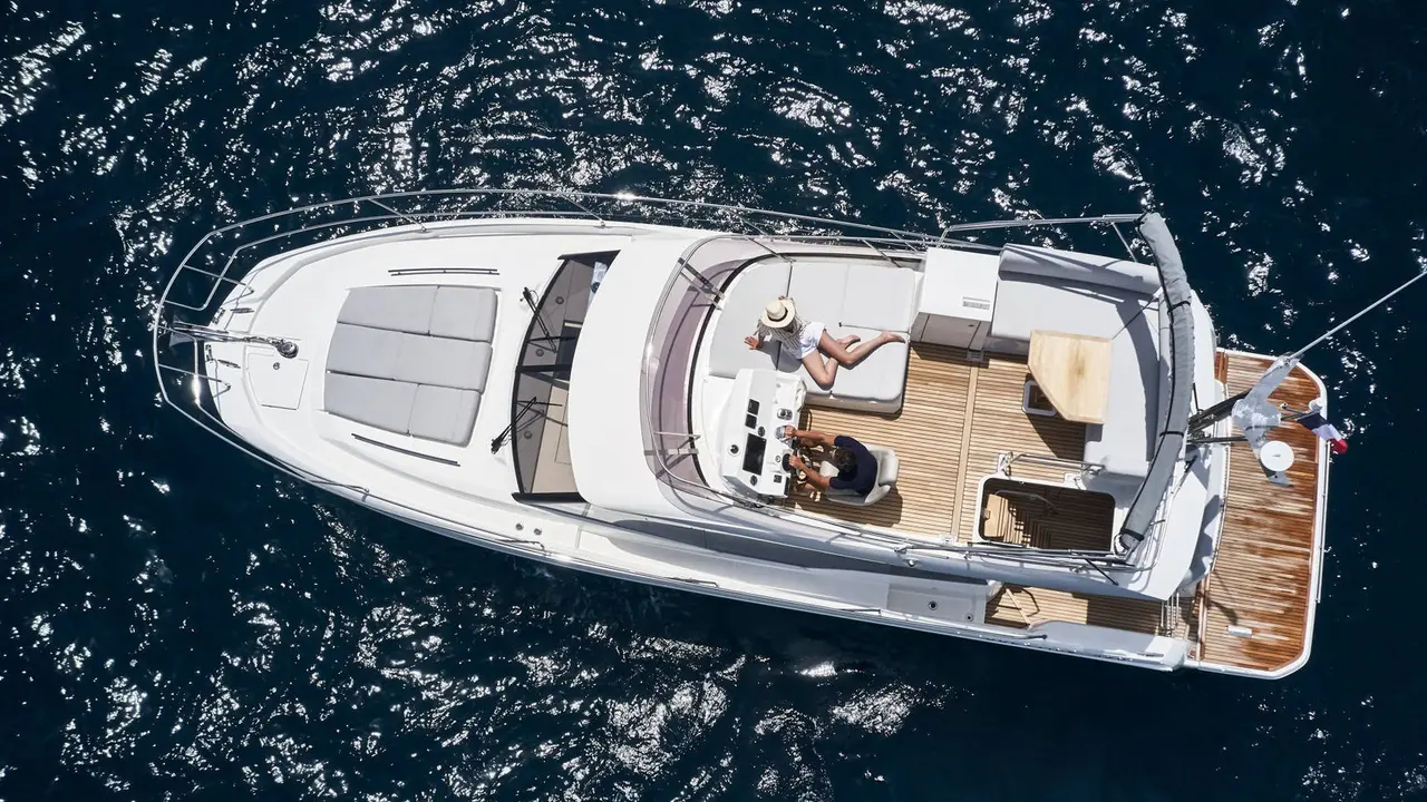 Aerial view of a luxury yacht from our fleet sailing in crystal-clear blue waters, featuring multiple decks, spacious lounging areas, and a sleek white exterior.