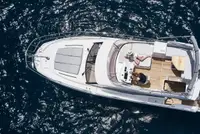 Aerial view of a luxury yacht from our fleet sailing in crystal-clear blue waters, featuring multiple decks, spacious lounging areas, and a sleek white exterior.