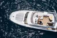 Aerial view of a luxury yacht from our fleet sailing in crystal-clear blue waters, featuring multiple decks, spacious lounging areas, and a sleek white exterior.