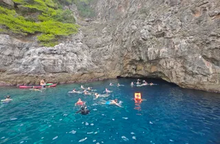 People swimming and snorkeling in the vibrant blue water of a cave near Dubrovnik, Croatia, during a private boat tour.