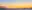 Serene sunset over calm sea with distant islands silhouetted against colorful sky gradient
