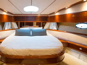 Luxury yacht interior: Spacious cabin with comfortable bed, wooden finishes, and ambient lighting for ultimate relaxation at sea