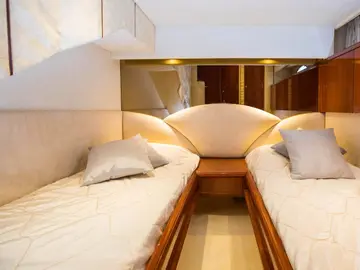 Luxurious yacht cabin with twin beds, plush pillows, and warm lighting. Elegant wood finishes and cozy atmosphere for Elafiti Islands cruise.