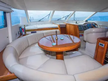 Luxury yacht interior: Elegant seating area with curved leather sofa, wooden table, and steering console on Elafiti Islands tour