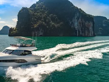 Luxury Prestige Yacht cruising through turquoise waters near lush coastal cliffs