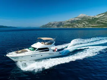 Luxury yacht cruising along Croatian coast near Dubrovnik, with Elaphiti islands and clear blue Adriatic Sea in background