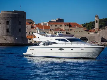 Luxury yacht sailing past Dubrovnik old town walls, Croatia.