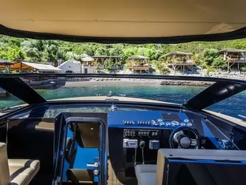 Luxury yacht cockpit view of serene coastal resort with bungalows & clear water, perfect for luxury Dubrovnik escape to islands.