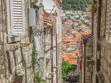 Narrow cobblestone street with stone staircase and terracotta pots of flowers in Dubrovnik Old Town, Croatia