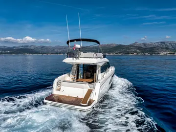 Luxury yacht cruising crystal blue Adriatic waters near Dubrovnik, Croatia, with stunning mountain backdrop under a clear sky.