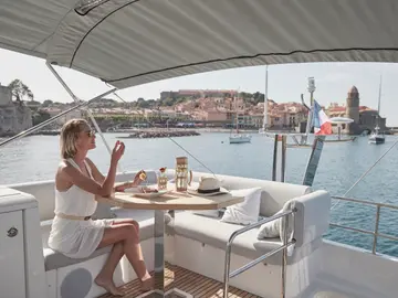 Woman enjoying a refreshing drink on a luxury yacht deck, overlooking a picturesque Dubrovnik coastal town and shimmering Adriatic Sea.
