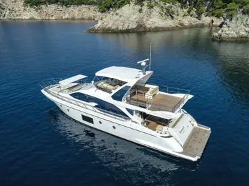 Azimut 66 Fly luxury yacht cruising the serene Adriatic Sea near Dubrovnik, with a rugged, green coastline in the background.