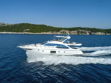 A sleek white Azimut 66 Fly luxury yacht cruises the deep blue Adriatic Sea near a lush green coastline, departing from Dubrovnik.