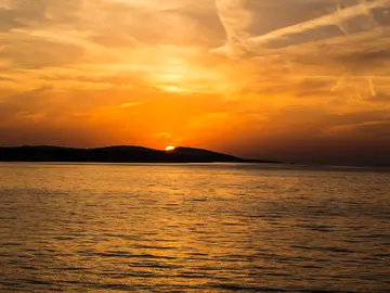 Golden sunset over Dubrovnik old town walls and Adriatic Sea viewed from hilltop trail