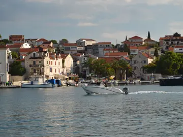 A white luxury boat sails past the picturesque Maslinica harbor on Šolta island, Croatia.