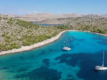 Aerial view of a catamaran and sailboats anchored in Croatia's Blue Lagoon, featuring incredibly clear turquoise water and lush islands, ideal for a private boat tour from Split.