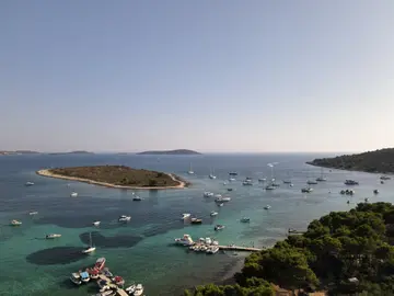 Aerial view of Dalmatian Blue Lagoon near Split with crystal-clear waters, a small island, and numerous boats.