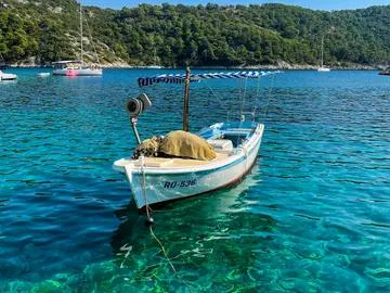White private boat on crystal-clear Adriatic Sea, showing visible seabed and lush Dalmatian coast for Split island hopping.