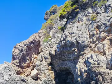 Luxury speedboat approaching a natural cave entrance on the clear blue Adriatic Sea near Dubrovnik, Croatia.