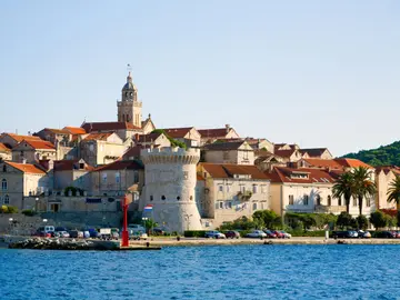 Korčula old town waterfront with medieval defensive walls and St Mark's Cathedral bell tower rising above the calm Adriatic Sea