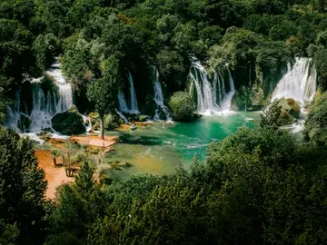 Turquoise swimming pool beneath Kravice Waterfalls on a sunny summer day in Bosnia and Herzegovina