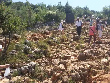 Pilgrims climbing the rocky path up Apparition Hill in Medjugorje, Bosnia and Herzegovina