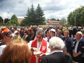 Outdoor Mass in Medjugorje with a priest distributing Holy Communion to a large crowd of pilgrims