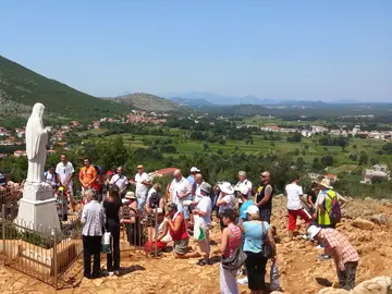 St. James Church in Medjugorje with twin bell towers and clock faces against a clear blue sky