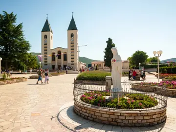 St. James Church in Medjugorje with the Virgin Mary statue in the foreground, garden and square