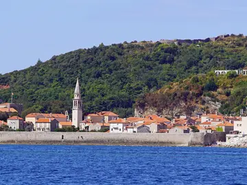Budva Old Town seen from the sea — medieval Venetian walls, terracotta rooftops and the bell tower of Saint Ivan, Montenegrin Adriatic coast