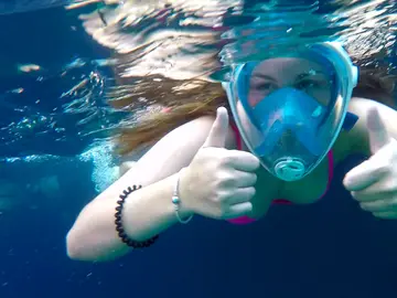 Client on the private boat journey underwater wearing full-face mask gives thumbs up sign.