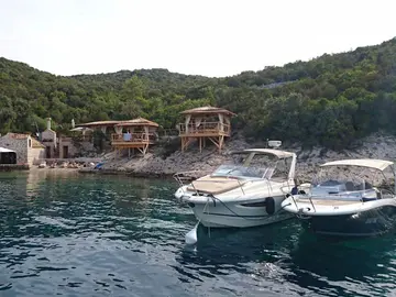 Secluded coastal cove with rustic buildings and moored boats, surrounded by lush green hills - a hidden gem near Dubrovnik, BOWA restaurant