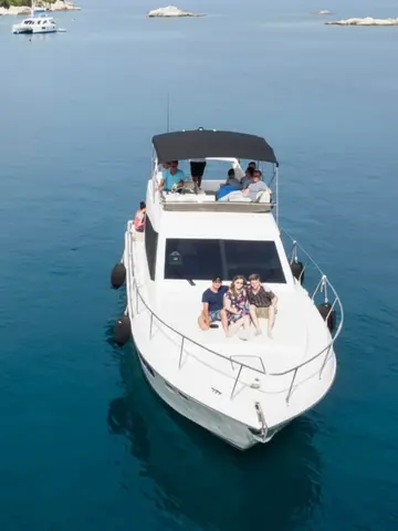 Aerial view of a luxury yacht charter cruising the crystal-clear turquoise waters of the Dubrovnik Elaphite Islands. A small group of friends or family enjoys a private boat tour, surrounded by stunning islands, perfect for an exclusive island hopping adventure or premium Dubrovnik vacation.