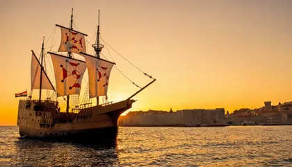 Dubrovnik luxury event ship sailing at sunset beside the Old Town city walls