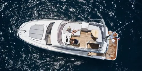 Aerial view of a luxury yacht from our fleet sailing in crystal-clear blue waters, featuring multiple decks, spacious lounging areas, and a sleek white exterior.