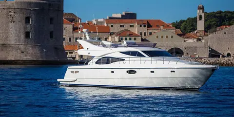 Luxury yacht sailing past Dubrovnik old town walls, Croatia.