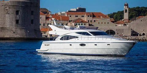 Luxury yacht sailing past Dubrovnik old town walls, Croatia.