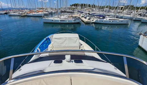 View from a motorboat in a vibrant Dubrovnik Frapa marina, packed with numerous sailing yachts and other vessels, under a clear blue sky.