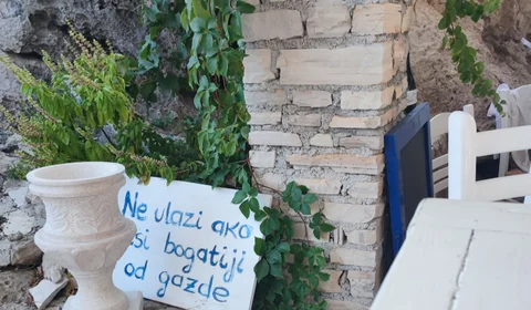 Charming Dubrovnik detail: White stone planter with handwritten sign in Croatian, green ivy, and rustic wall texture