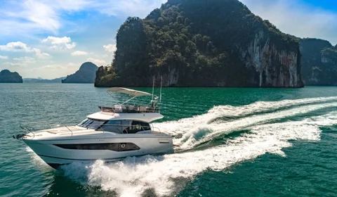 Luxury Prestige Yacht cruising through turquoise waters near lush coastal cliffs