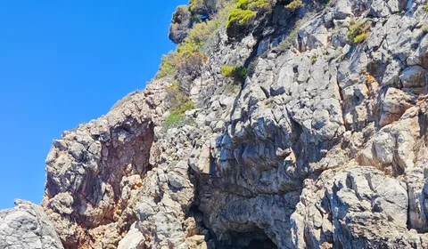 Luxury speedboat approaching a natural cave entrance on the clear blue Adriatic Sea near Dubrovnik, Croatia.