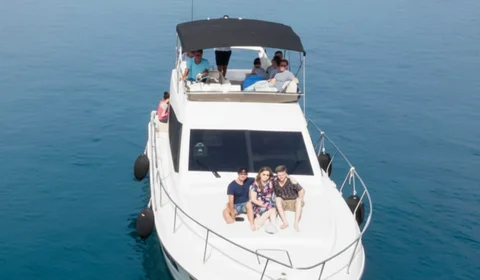 Aerial view of a luxury yacht charter cruising the crystal-clear turquoise waters of the Dubrovnik Elaphite Islands. A small group of friends or family enjoys a private boat tour, surrounded by stunning islands, perfect for an exclusive island hopping adventure or premium Dubrovnik vacation.