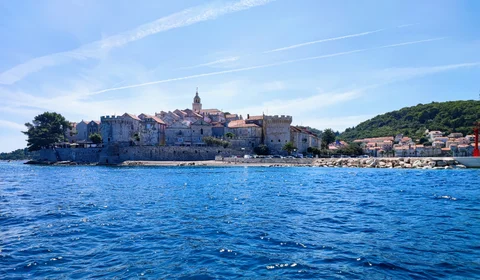 View of the walled town of Korcula from the sea, showcasing its historic architecture and beautiful waterfront.