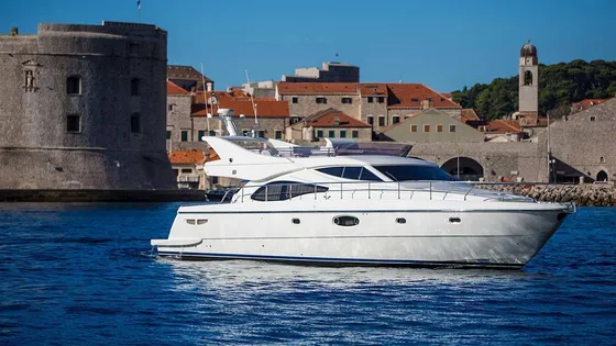 Luxury yacht sailing past Dubrovnik old town walls, Croatia.